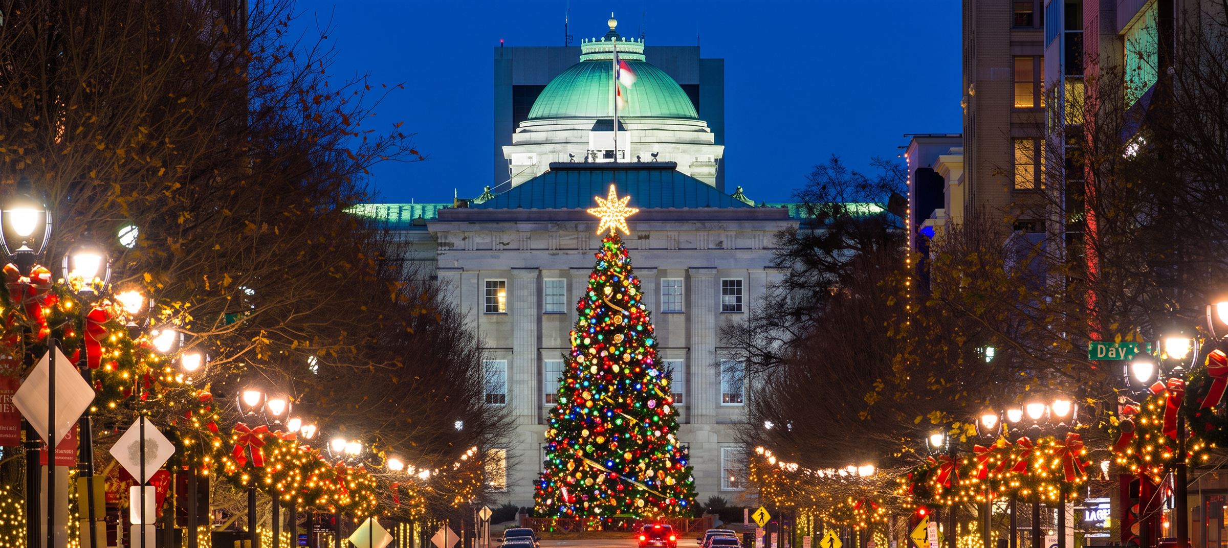 Downtown Raleigh at night: the State Capitol and its glowing Christmas tree at the end of a street wrapped in lights